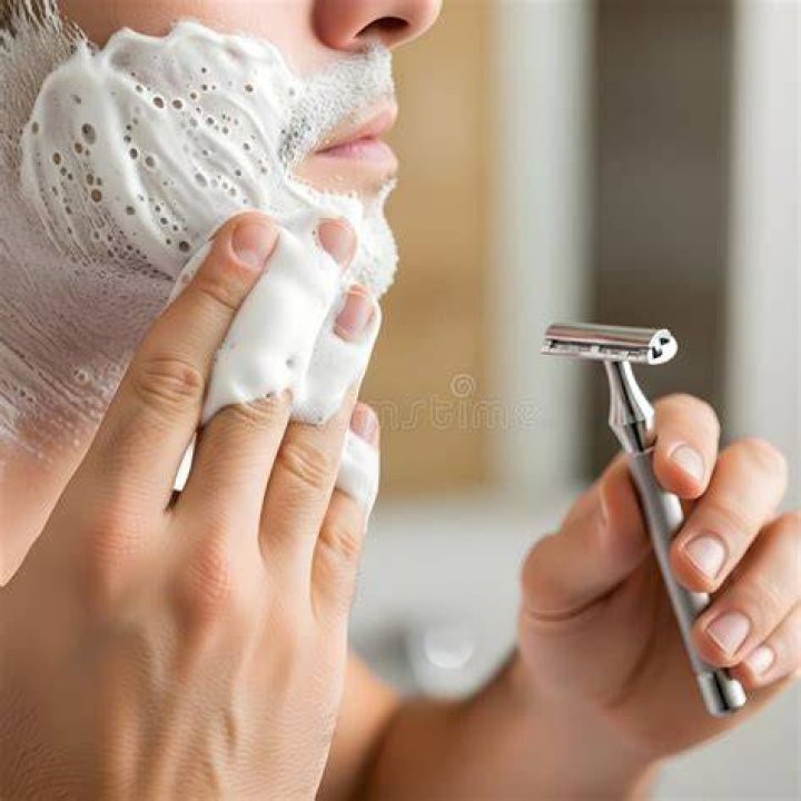 A man applies shaving cream after a shower.