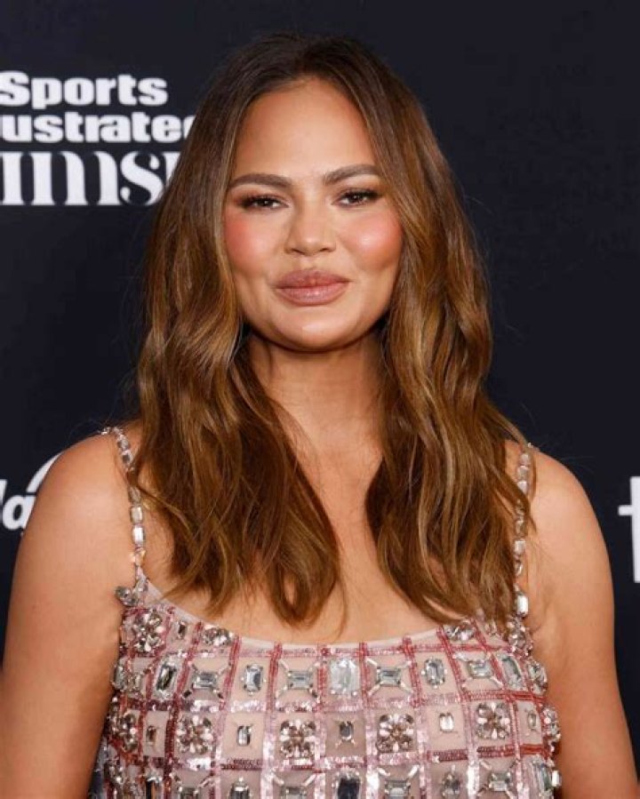 Chrissy Teigen Rocks Bike Shorts, High Boots & ‘Michelle Obama’-Inspired Gold Belt For Dress Up Look